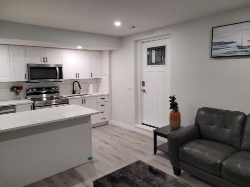 a living room with a couch and a kitchen at Coastal Comforts Villa in Airdrie