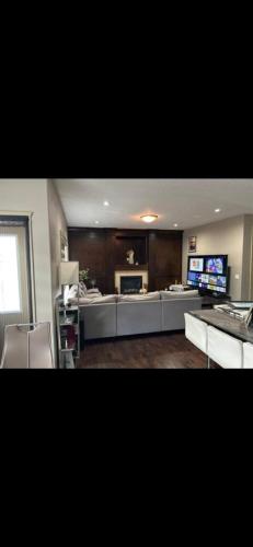a living room with a couch and a television at Coastal Comforts Villa in Airdrie