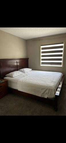 a large bed in a bedroom with a window at Coastal Comforts Villa in Airdrie