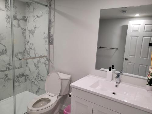 a bathroom with a toilet and a sink and a shower at Coastal Comforts Villa in Airdrie