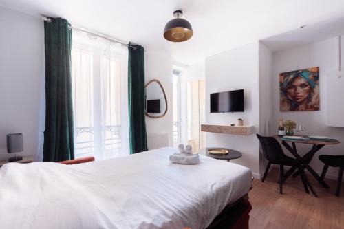 a bedroom with a white bed and a table with chairs at Studio rénové - Accès direct Paris in Montreuil