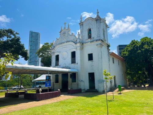 an old white building with a tower in a park at Flat Parque da Jaqueira in Recife