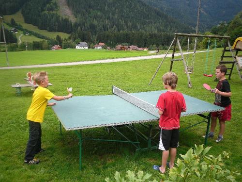 three children playing on a ping pong table in a field at Pension & Ferienwohnung Sonnleiten in Gnesau