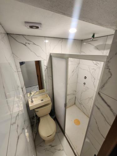 a bathroom with a toilet and a sink and a mirror at Hotel Alambique Arandas in Arandas