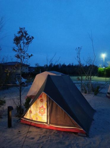 a tent that is sitting in the sand at night at iwado base in Tottori