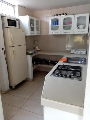a kitchen with a stove and a white refrigerator at Melgar Casa Piedras del Agua in Estación El Salto