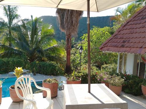 a white table and chair under an umbrella next to a pool at Melgar Casa Piedras del Agua in Estación El Salto