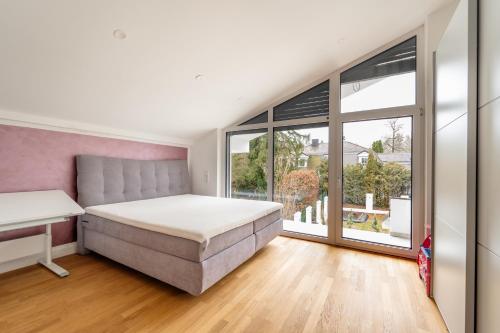 a bedroom with a bed and a large window at Exklusive Walmdachvilla München-Grünwald in Grünwald