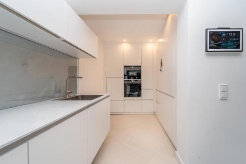 a kitchen with white cabinets and a sink at Exklusive Walmdachvilla München-Grünwald in Grünwald