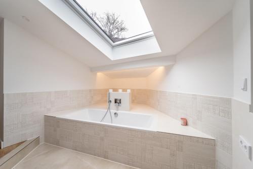 a bath tub in a bathroom with a skylight at Exklusive Walmdachvilla München-Grünwald in Grünwald