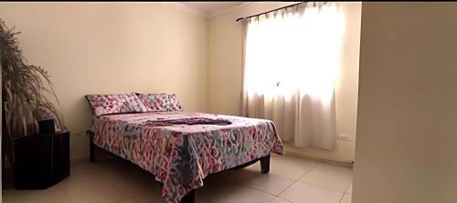 a bedroom with a bed with a pink blanket and a window at Martina II Stay in Santo Domingo
