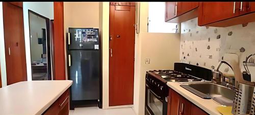 a kitchen with a black refrigerator and a sink at Martina II Stay in Santo Domingo