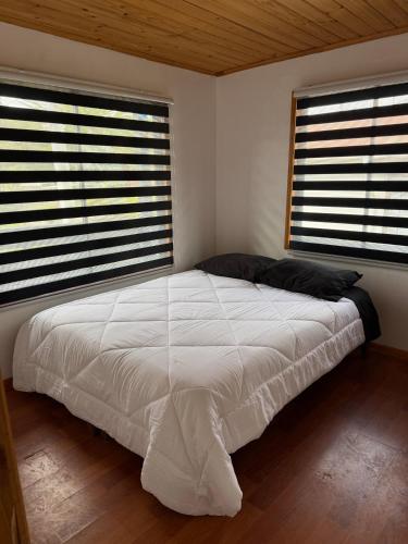 a bedroom with a large white bed with two windows at House 1 Pichilemu Lake in Pichilemu