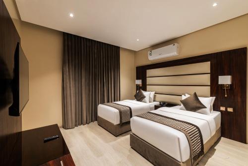 a hotel room with two beds and a television at فندق فيو الشاطي - Beach View Hotel in Dammam