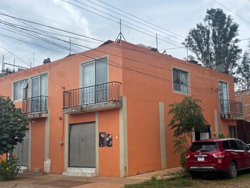 a red car parked in front of a orange building at Depa Perdiz in Tepatitlán de Morelos