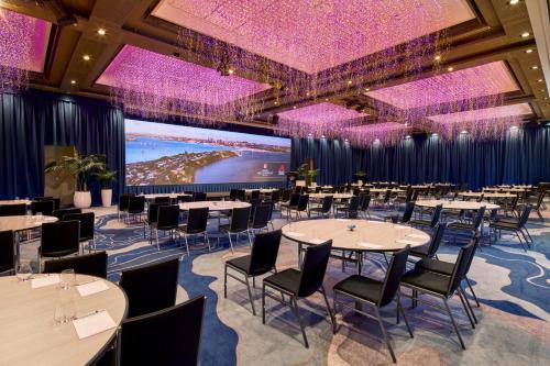 a banquet hall with tables and chairs and a projection screen at Grand Millennium Auckland in Auckland