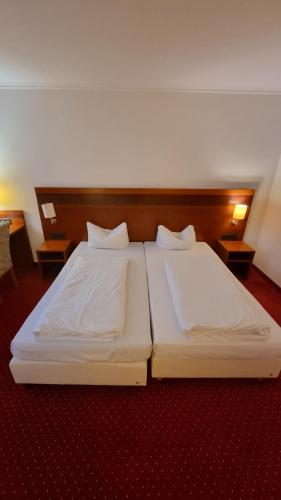 two beds in a hotel room with white sheets at Hotel am Rosenpark in Aachen