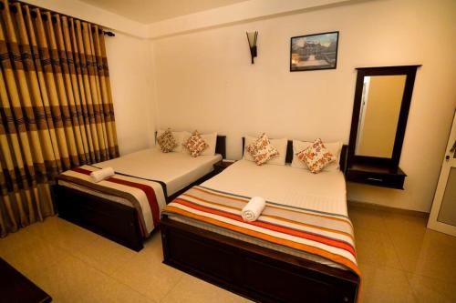 two twin beds in a room with a mirror at Airport 4 Season Transit Hotel in Katunayake
