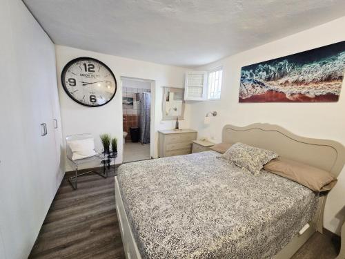 una camera da letto con un letto e un orologio a parete di Apartamentos Medano - Casa Playa a El Médano