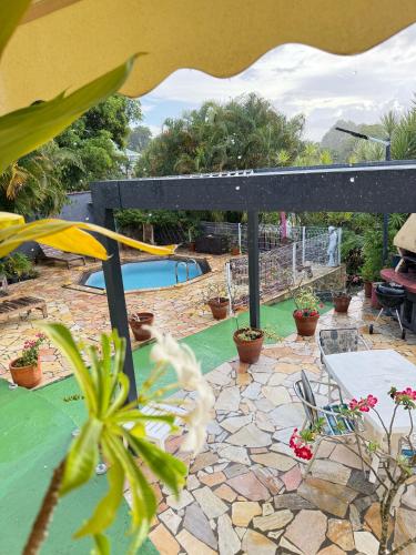 un patio con piscina, tavolo e sedie di VILLA SAFRAN a Sainte-Anne