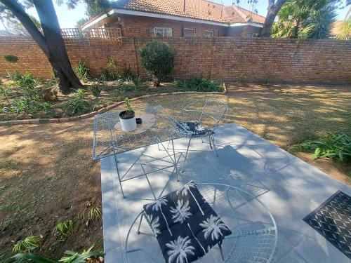 a glass table with a chair in a yard at Dragonfly in Boksburg