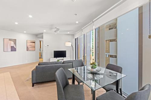 a living room with a glass table and chairs at Spire Residences by CLLIX in Brisbane