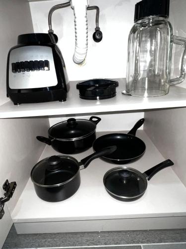 four black pots and pans on a shelf in a kitchen at BIT by Simple stay in Medellín
