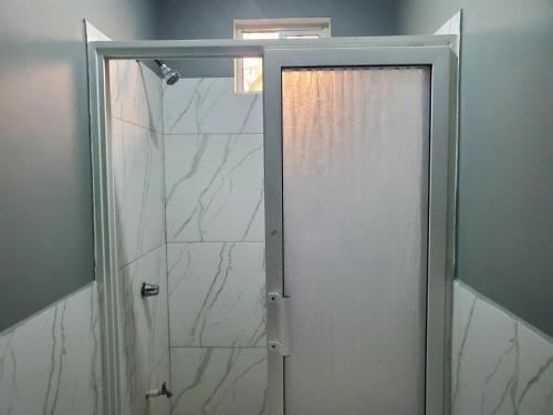 a glass shower door in a bathroom with a window at Apartamento acogedor, minutos de Playa Camaguey #5 in Puerto Cortes