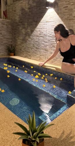 a woman in a black dress sitting next to a swimming pool at Casa Moka Azul in La Peñita de Jaltemba