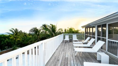 a wooden deck with white chairs on it at Bahama Mama home in Governorʼs Harbour