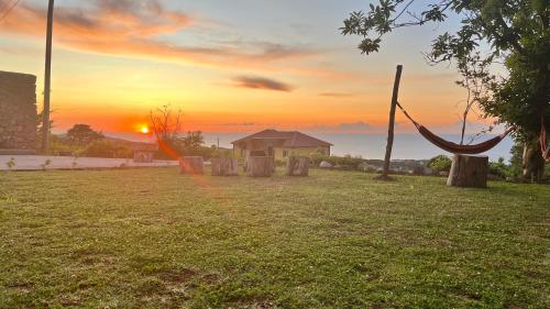 a sunset over the ocean with a hammock in a field at Biscoitos Top View in Biscoitos