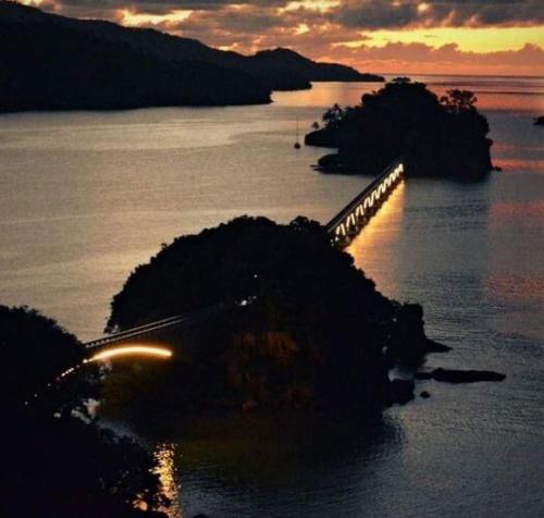 a bridge over the water with a sunset in the background at Acogedor apartamento en Samaná con vista al mar in La Aguada