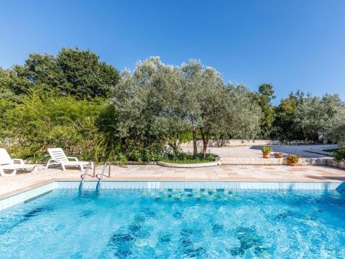 a swimming pool with chairs and trees in the background at in the swimming pool Villa Brioni 2 in Peroj