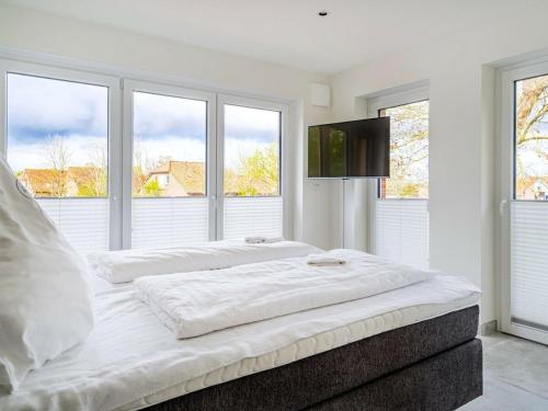 a white bedroom with two beds and a flat screen tv at Holiday apartment with 2 bedrooms in Greetsiel