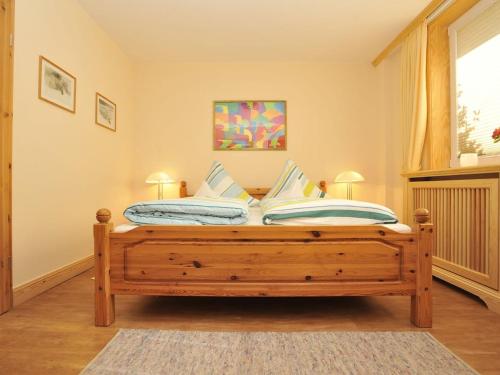 - une chambre avec un lit en bois et 2 oreillers dans l'établissement Süderhof Apartment 3, à Keitum