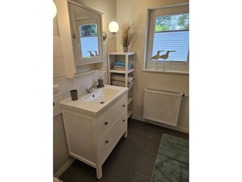 La salle de bains est pourvue d'un lavabo, d'un miroir et de 2 fenêtres. dans l'établissement "House on the Guest", à Dangast