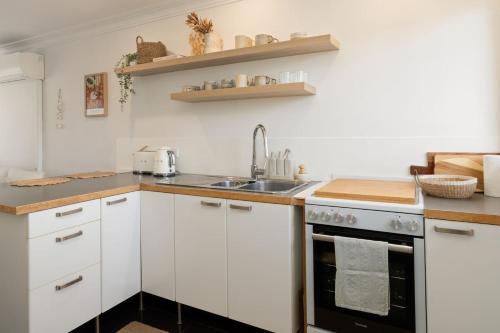 a kitchen with white cabinets and a sink at Bilinga Breeze - Walk to North Kirra Beach and Airport in Gold Coast