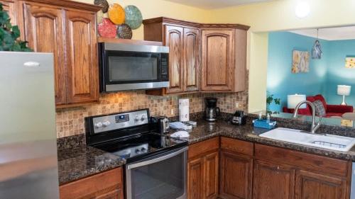 une cuisine avec des armoires en bois et un four à plaques de cuisson dans l'établissement Island Condo 1st Floor Pool Patio condo, à South Padre Island