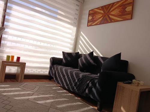 a living room with a black couch and a window at Acogedor Dpto en Llanquihue in Llanquihue