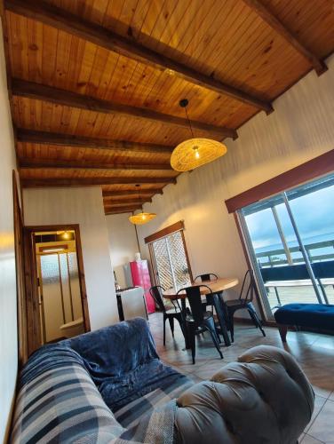 a living room with a couch and a table with chairs at Cabañas Refugio Costero in Las Lomas