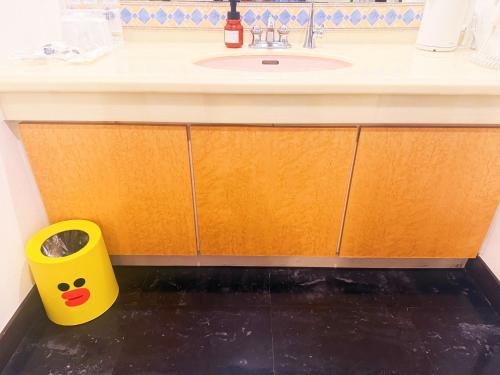 a bathroom with a sink and a yellow trash can at Ikaho no mori Kids Paradise in Ikaho