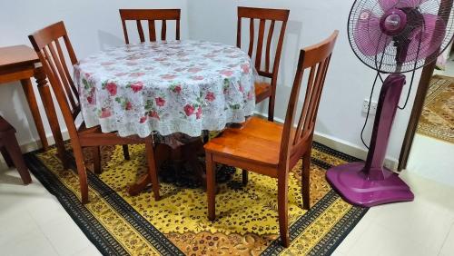 a table and chairs with a table and a fan at Liza Homestay in Bachok