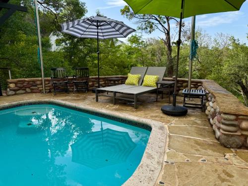 a swimming pool with two chairs and an umbrella at The Rivery Retreat, Choose from Luxury Guesthouse Cabin OR Poolside Suite in Lake Austin Hill Country in Austin