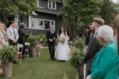 a bride walking down the aisle with her father at Bonnie View Inn in Haliburton