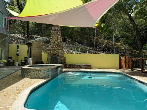a large swimming pool with a colorful umbrella over it at The Rivery Retreat, Choose from Luxury Guesthouse Cabin OR Poolside Suite in Lake Austin Hill Country in Austin