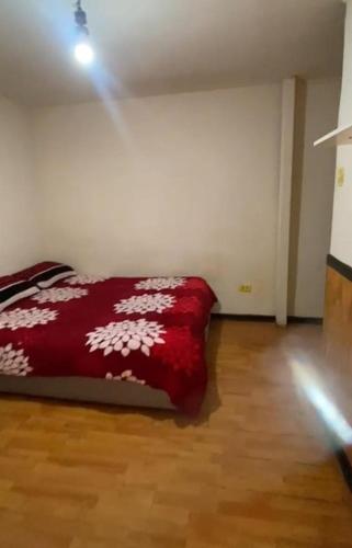 a bedroom with a red bed with white flowers on it at Hostal centro in La Serena