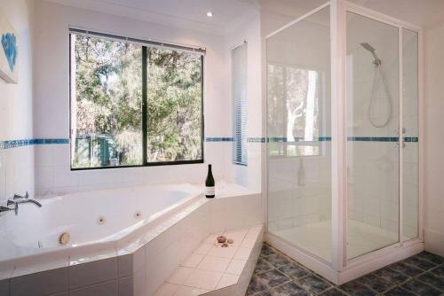 une salle de bain blanche avec une baignoire et une fenêtre dans l'établissement Idyll Estate - Bushland Gem with Spa & Tennis Court, à Yallingup Siding