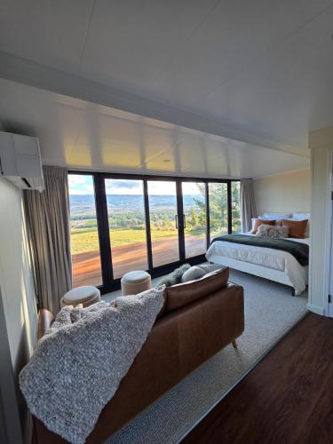 a bedroom with a couch and a bed and a large window at Modern studio overlooking Alexandra, Central Otago in Alexandra