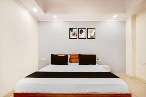 a bedroom with a large white bed with black pillows at HOTEL O BLUE DIAMOND STAY in Noida