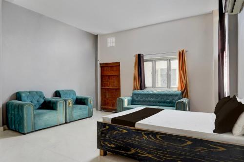 a bedroom with two blue chairs and a bed at Hotel O Raj Palace in Bāra Banki